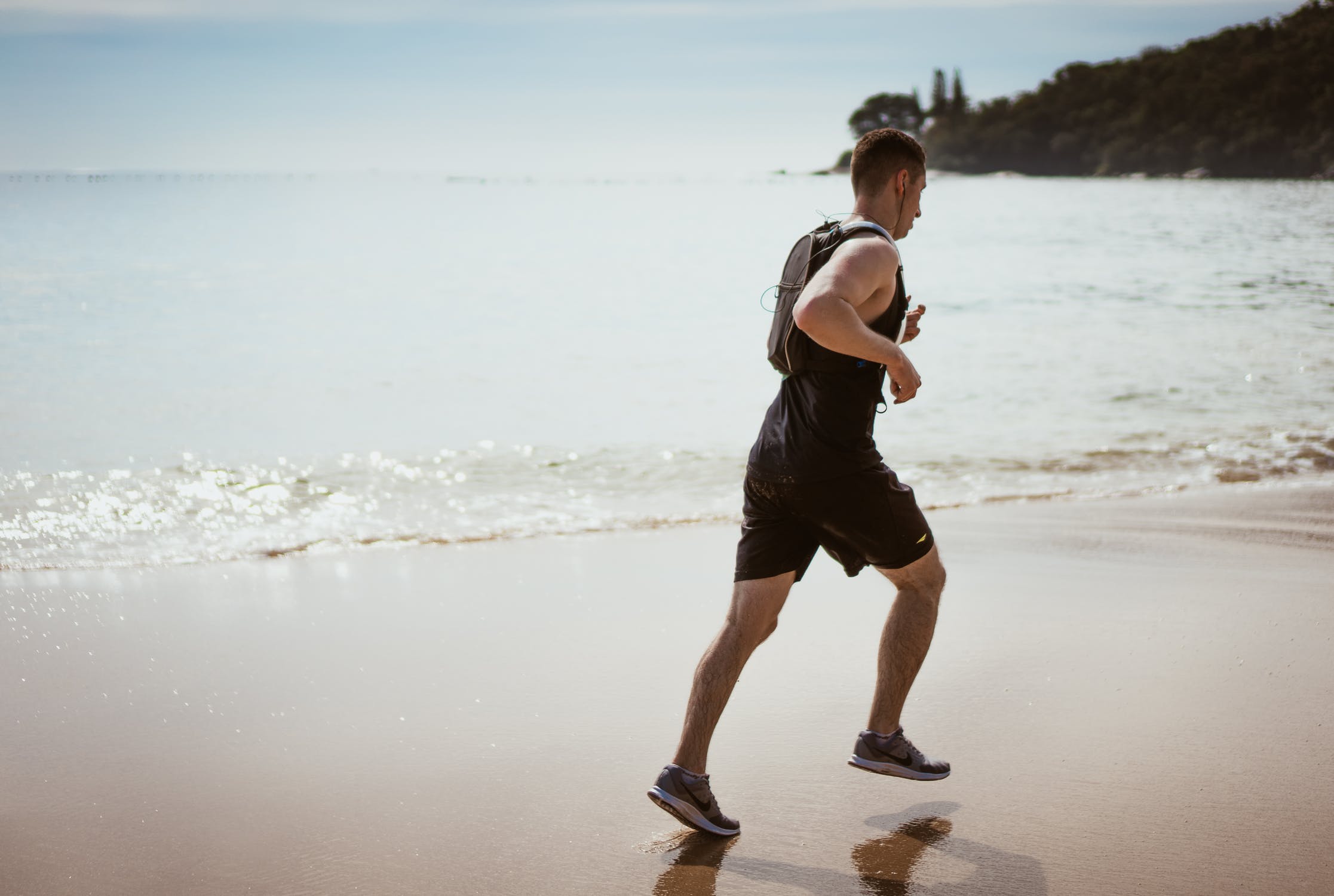 Man running across beach keeping fit